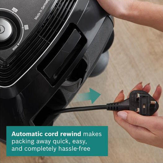 Person unplugging a black appliance with an automatic cord rewind feature.