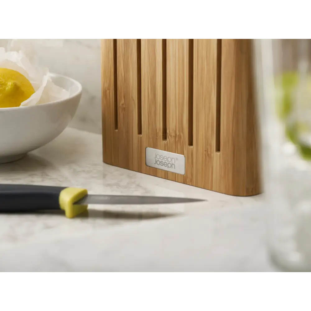 Joseph Joseph Elevate knife block set in natural bamboo with five kitchen knives displayed on marble countertop next to lemon and white bowl