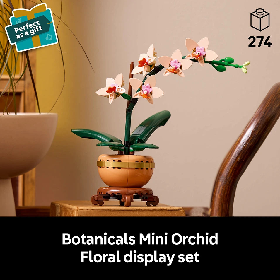 LEGO Botanicals Mini Orchid floral display set 10343 featuring buildable white and pink orchid flowers with green leaves in a terracotta pot with wooden stand, displayed on wooden surface with warm interior styling, 274 pieces, perfect as a gift