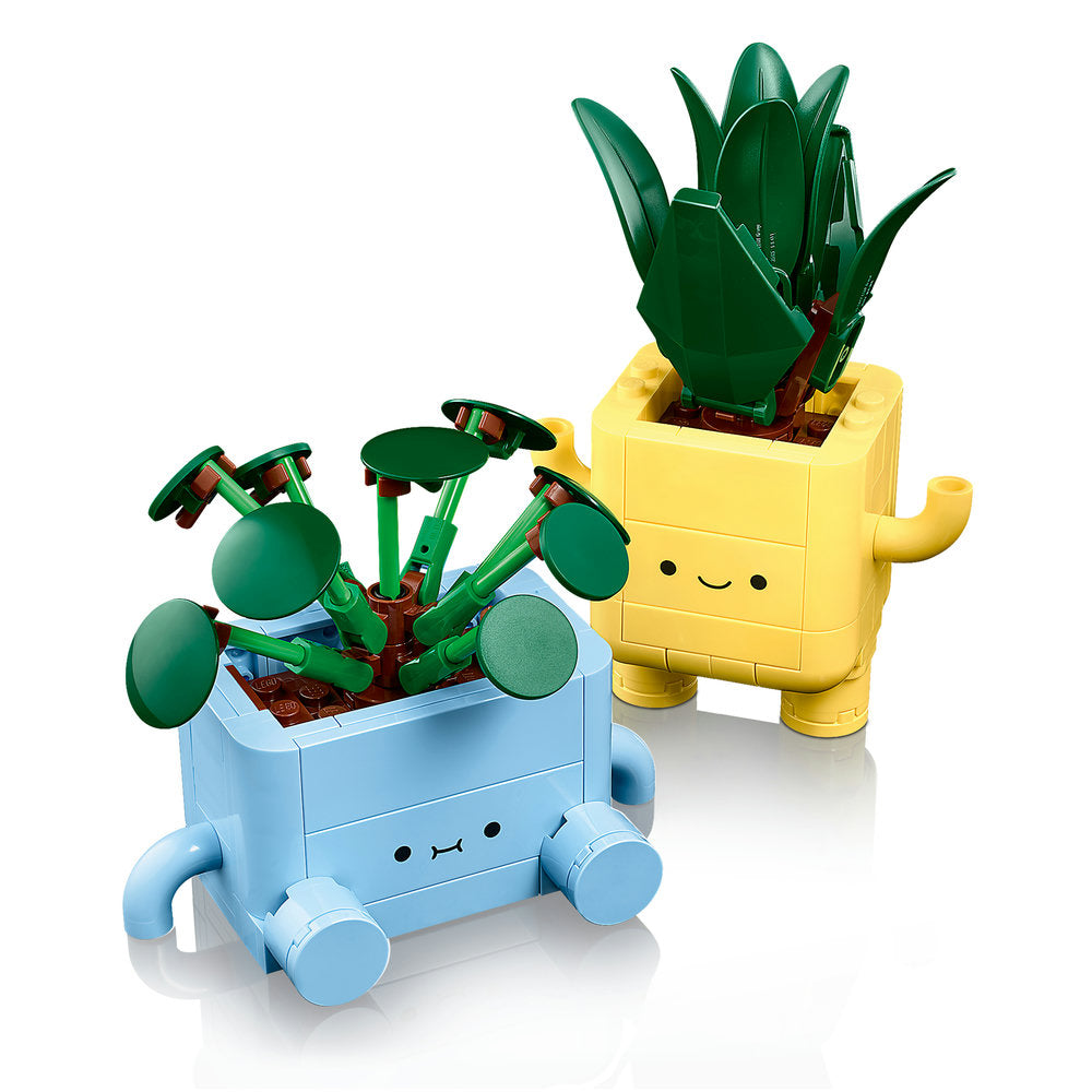 LEGO Happy Plants 10349 set featuring two buildable potted plants with smiling faces - a blue pot with round green leaves on wheels and a yellow pot with tall green cactus-like leaves, both constructed from colorful LEGO bricks