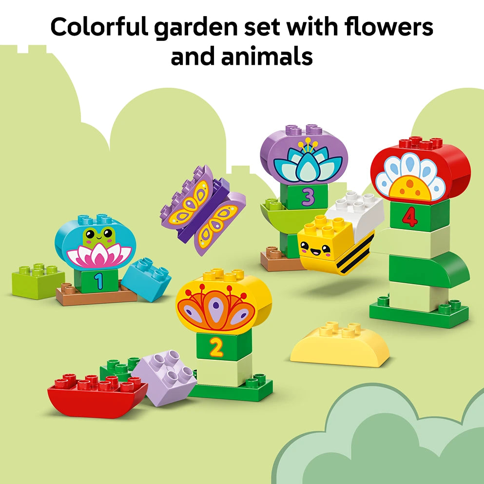 Colorful LEGO Creative Garden and Flowers building set 10444 featuring numbered flower blocks with cute animal faces in bright primary colors including blue, purple, red, yellow and green pieces arranged on a light green background with decorative cloud elements