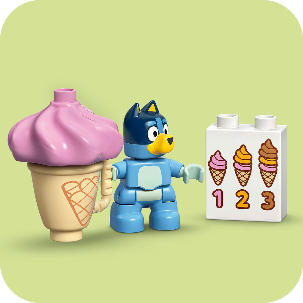 LEGO Ice Cream Trip with Bluey set 10458 featuring a blue LEGO Bluey character figure, pink ice cream cone with waffle cone design, and white numbered ice cream flavor selector brick with three colorful ice cream illustrations on pale yellow background