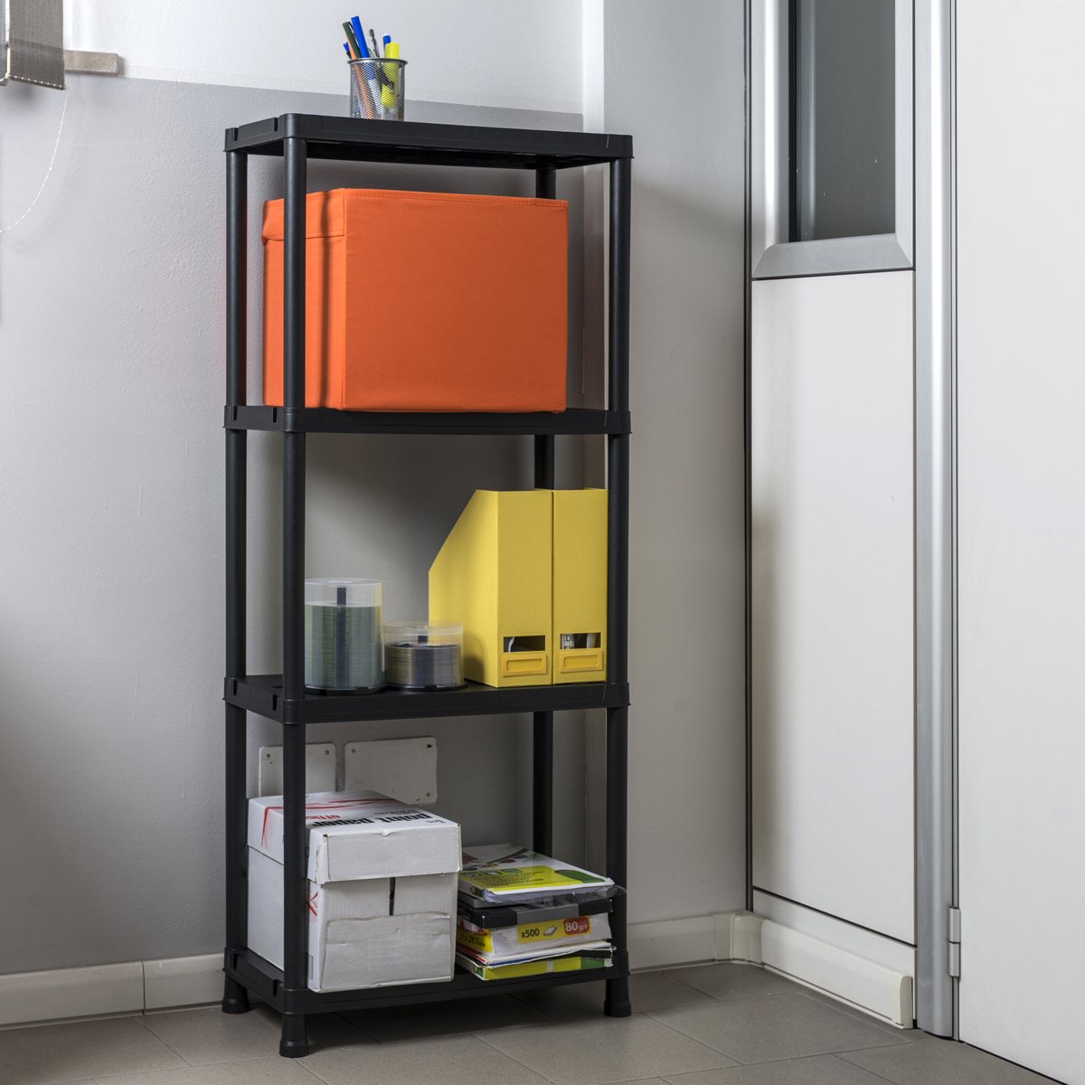 Black metal shelf with orange, yellow, and white boxes against a gray wall.