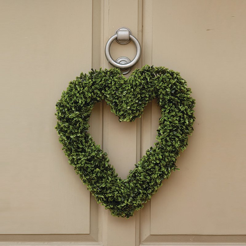Heart-shaped boxwood topiary wreath in vibrant green hanging on a cream-coloured door with a silver ring knocker, 40cm decorative garden ornament