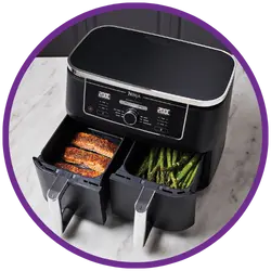 Black air fryer with food items inside on a white background