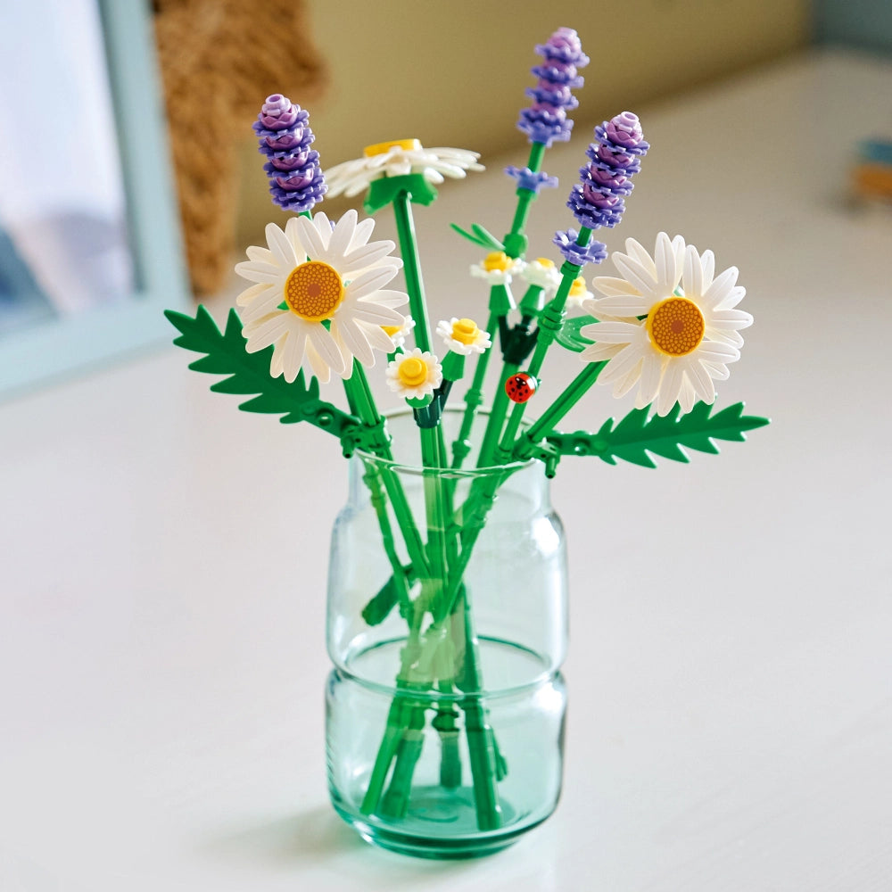 LEGO Daisies buildable flower set in glass vase featuring white daisies with yellow centers, purple lavender sprigs, green stems and leaves, and a red ladybug accent piece
