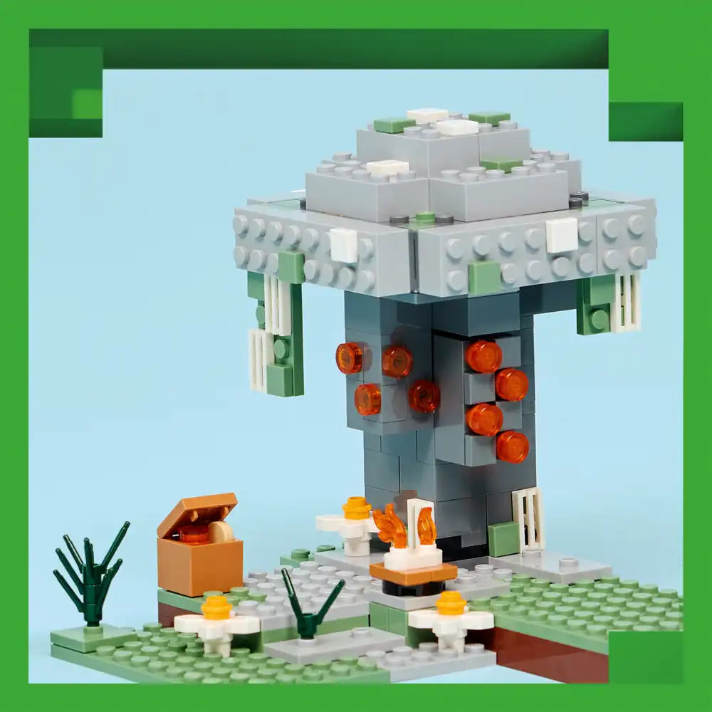 LEGO Minecraft Pale Garden set featuring a grey tower structure with orange glowing orbs, white and green base platform with grass, flowers, plants, and a brown chest, displayed against light blue background with green border