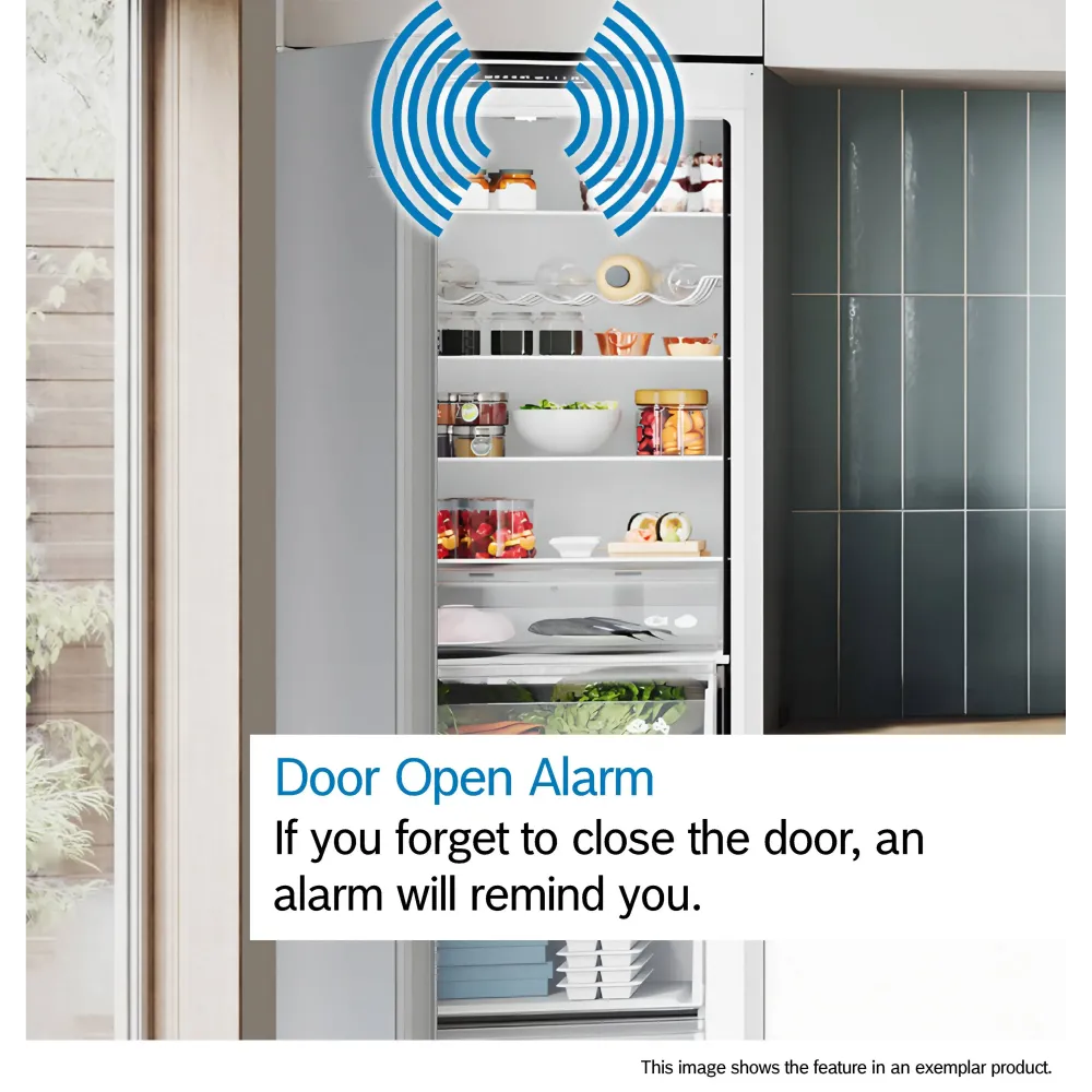 Bosch Series 2 white fridge freezer with door open alarm feature illustrated by blue sound wave icon, showing organized shelves with fresh produce, condiments and kitchenware, modern kitchen setting with dark green cabinetry visible to the right