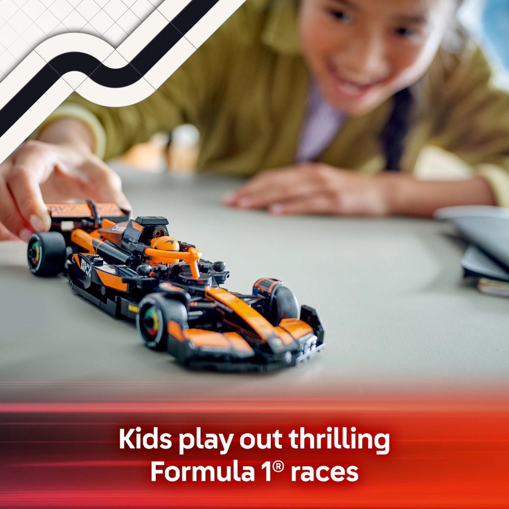 Child playing with orange and black LEGO McLaren F1 race car model on white surface with blurred child in olive green shirt in background
