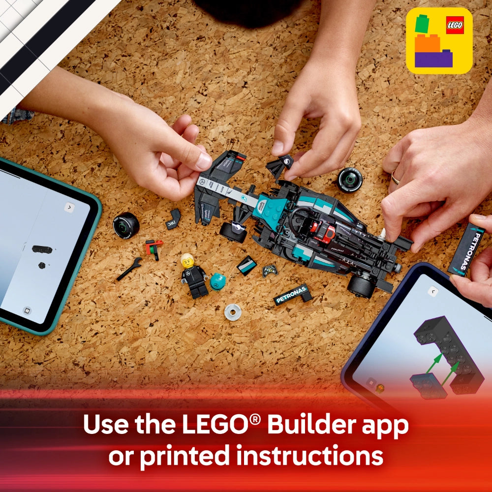 Child's hands assembling a turquoise and black LEGO Mercedes-AMG F1 W15 race car set on a cork surface with scattered LEGO pieces, minifigure, and instruction manuals on tablets nearby, demonstrating building with the LEGO Builder app