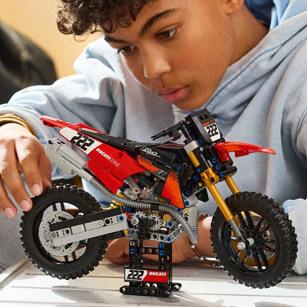 LEGO Technic Ducati Desmo450 MX Factory Motorcycle 42238 - a child playing with the finished build. 457 pieces. Ages 10+.