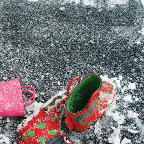 Hug Rug Doormat 50cm x 75cm in Charcoal color displayed outdoors on snowy ground with a child's red and green patterned boot and pink bucket, showing the mat's textured surface and durability in winter conditions