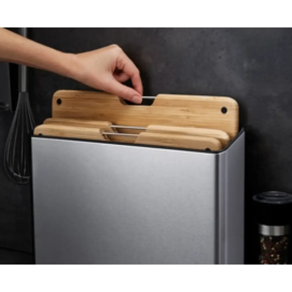Joseph Joseph Folio Steel Bamboo 3 Piece Chopping Board Set with stainless steel container and natural bamboo boards being removed by hand, displayed against dark background with kitchen utensils