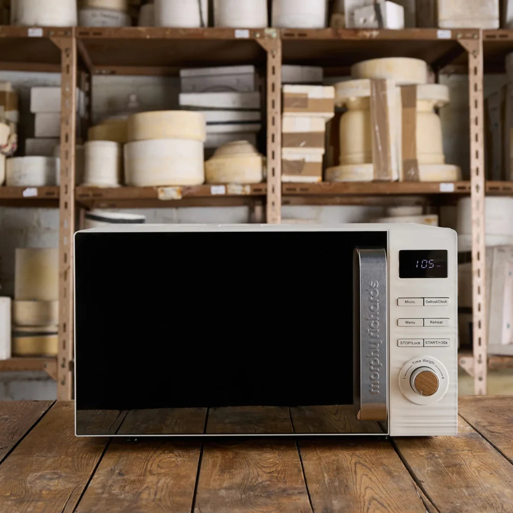 Morphy Richards Clay 20 litre 800w microwave in china white with digital display and control panel, positioned on wooden surface with storage shelves of cream-colored kitchenware in background