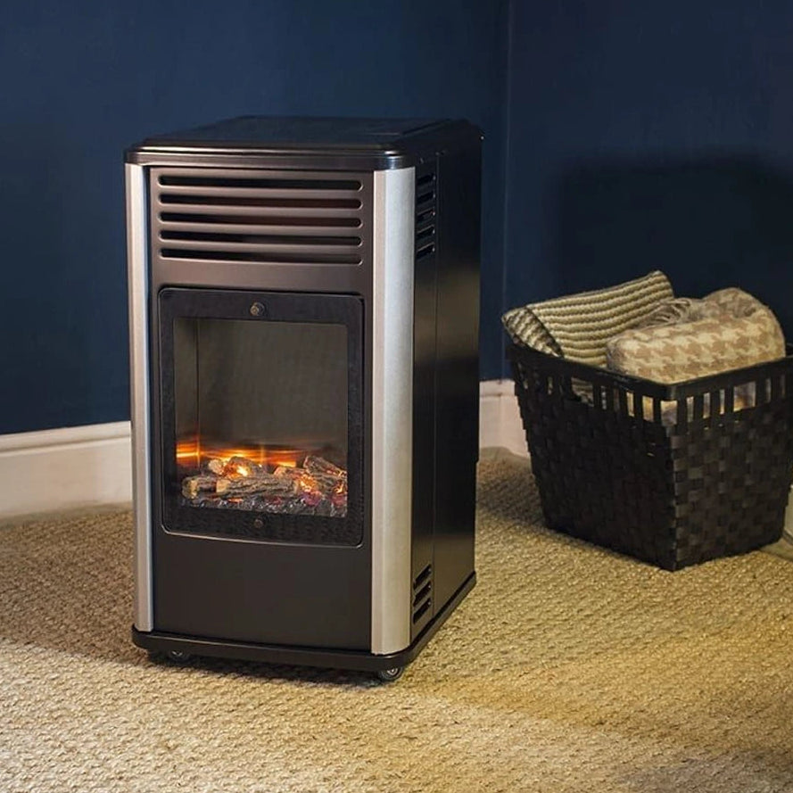 Manhattan Portable Gas Fire Heater 3.4kw with black and silver finish displaying glowing flames in living room setting next to black wicker basket with blankets on beige carpet against dark blue wall