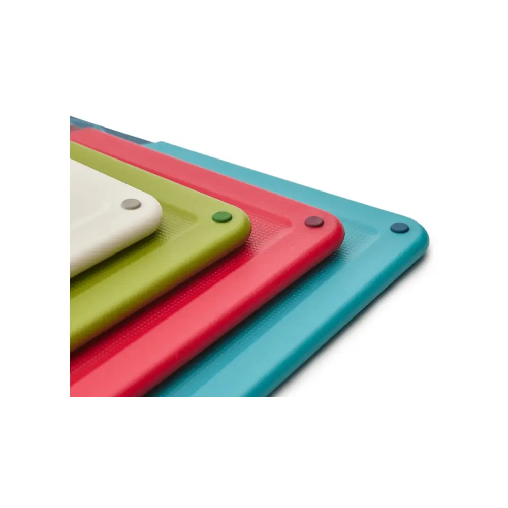 Four colorful Joseph Joseph Folio chopping boards stacked in white, lime green, coral red, and teal blue with textured surfaces and gray corner pegs, displayed in a 3D perspective view