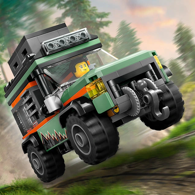 LEGO off-road 4x4 mountain truck set 60447 featuring a green and orange rugged vehicle with black wheels, roof rack with lights, and yellow minifigure driver, shown in action on a forest road with evergreen trees in background