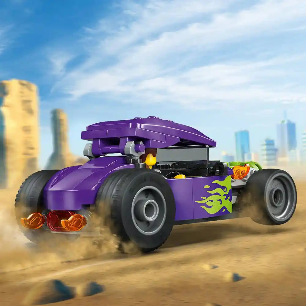 LEGO Hot Rod 60485 purple brick-built race car with yellow flame decals, large black tires, and orange rear lights displayed against a desert landscape with city skyline backdrop