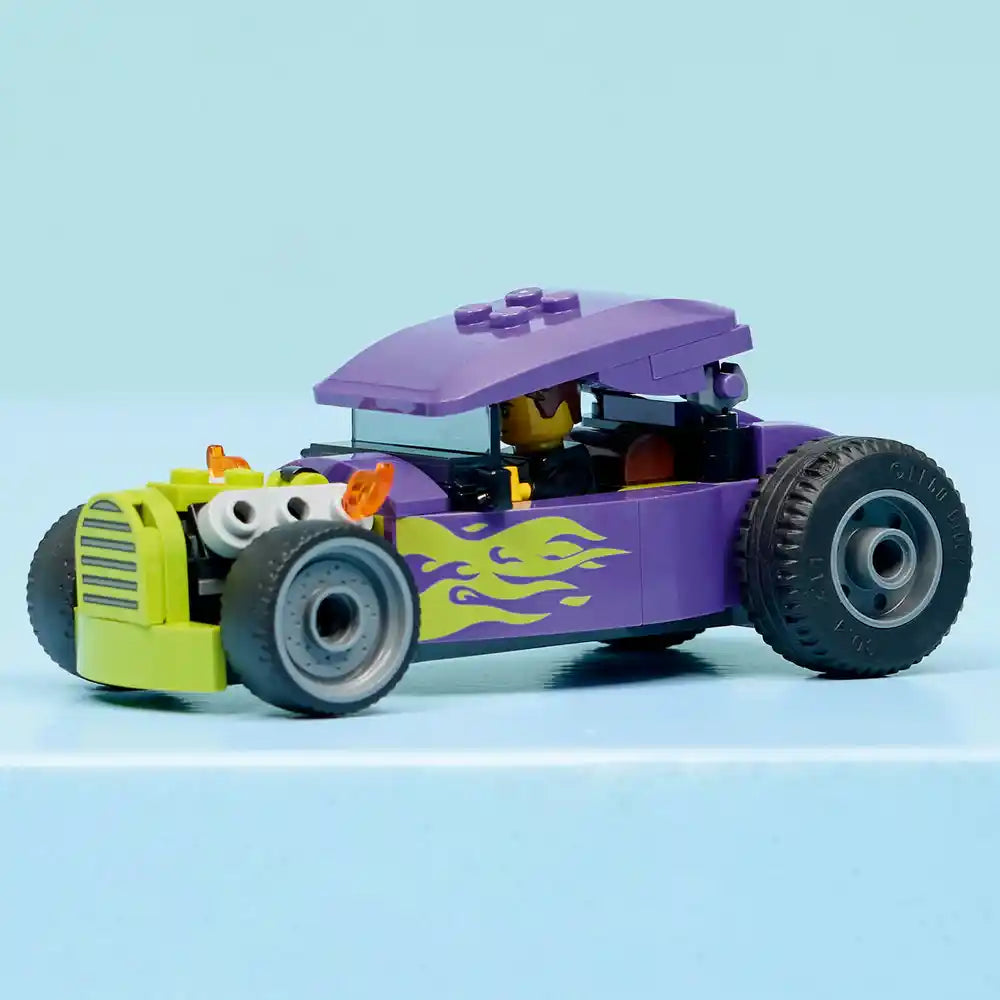 LEGO Hot Rod 60485 purple and lime green buildable car toy with flame decals, oversized black wheels, white goggle eyes, and removable purple canopy roof against light blue background