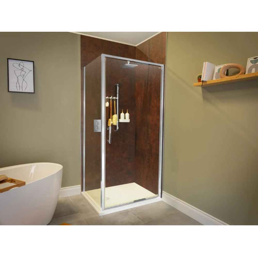 Modern bathroom featuring a chrome-framed glass infold shower door with rust-effect brown wall panels, rectangular rainfall showerhead, and white shower tray, positioned in corner next to freestanding white oval bathtub with wooden bath caddy, sage green walls, grey floor tiles, and minimalist decor including line art print and floating wooden shelf