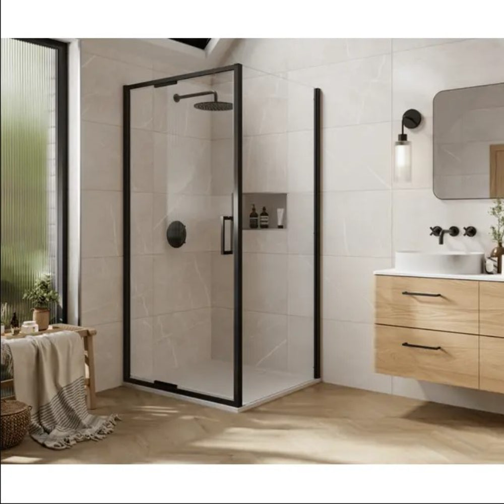 Modern bathroom featuring a matte black framed glass shower enclosure with infold door, rainfall showerhead, and built-in wall niche. The space includes light beige marble-effect wall tiles, herringbone wood-effect flooring, a wall-mounted oak vanity unit with white vessel sink, black wall-mounted faucet, and a rounded mirror with wall sconce lighting
