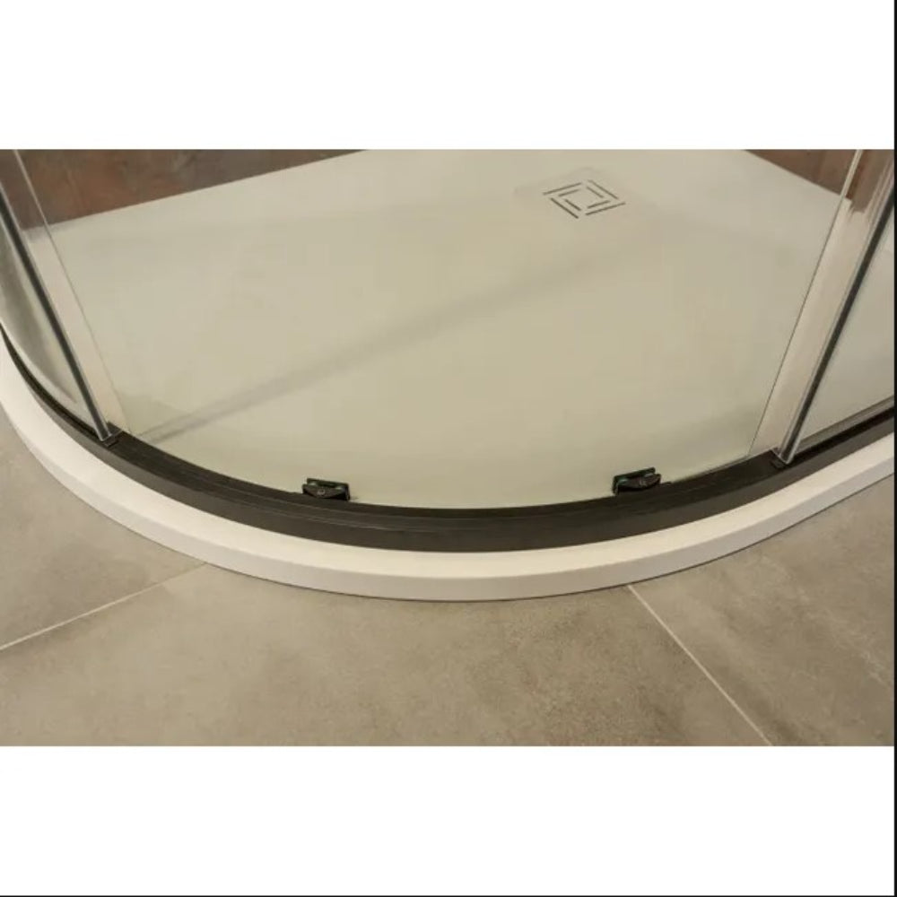 Quadrant shower enclosure base with curved glass sliding doors featuring black frame and rollers, white low-profile shower tray with square drain cover, installed on beige tile flooring in modern bathroom setting