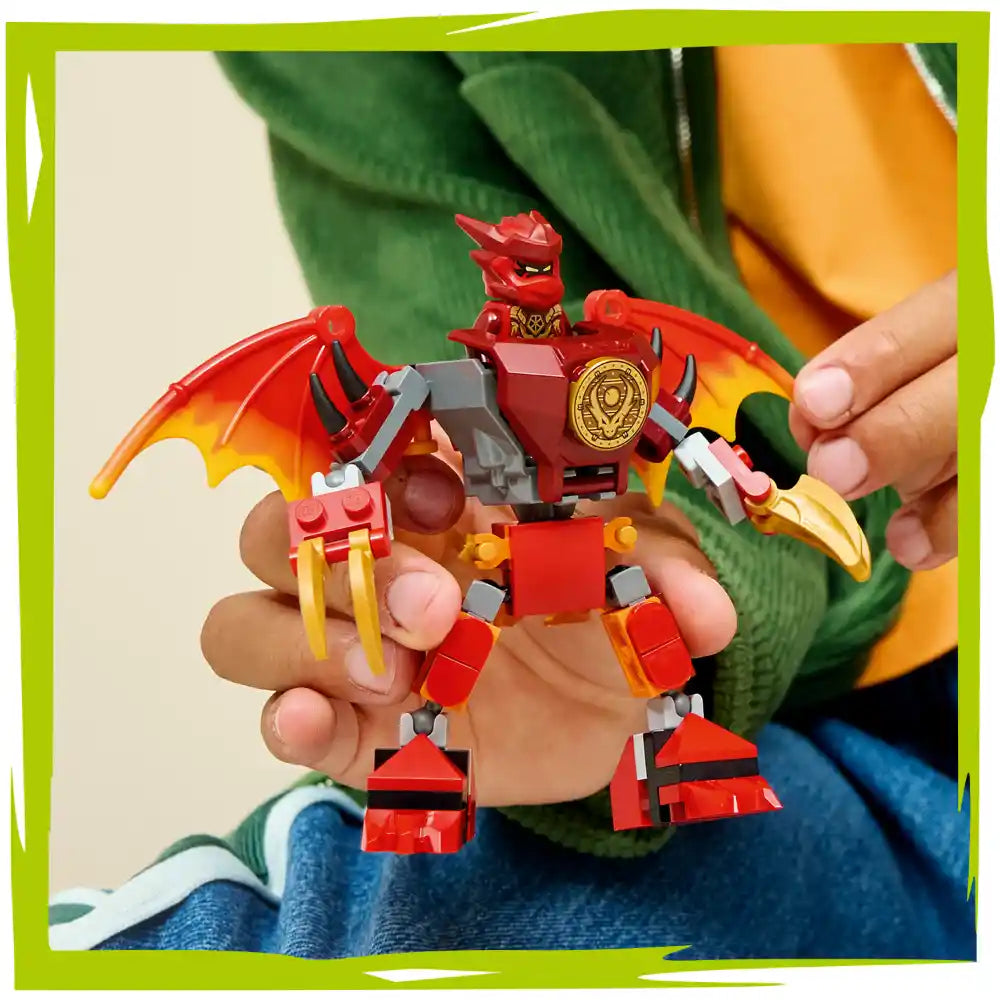 Child holding a red and gold LEGO Ninjago dragon mech figure with articulated wings, mechanical body, and detailed armor pieces against a green leaf background