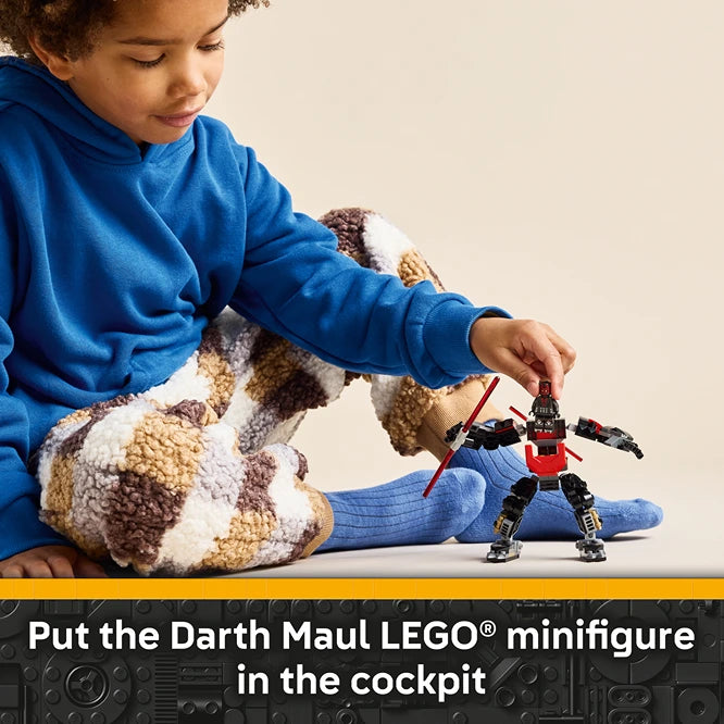 Child in blue hoodie and blue socks playing with LEGO Darth Maul Mech set, positioning red and black minifigure in cockpit of buildable mech robot