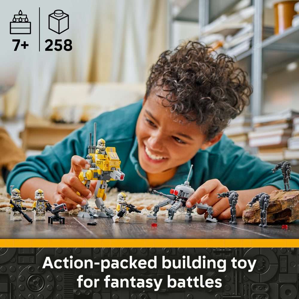Young child playing with LEGO Star Wars 75431 Clone Troopers Battle set, featuring yellow and grey minifigures, buildable vehicles and soldier pieces on display surface, with 7+ age recommendation and 258 pieces shown in top left corner