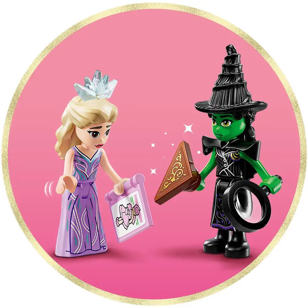 LEGO Wicked minifigures on pink background featuring blonde princess character in purple dress with ice crown holding spell card, and green-skinned witch in black hat and outfit holding magical mirror, gold glitter border frame