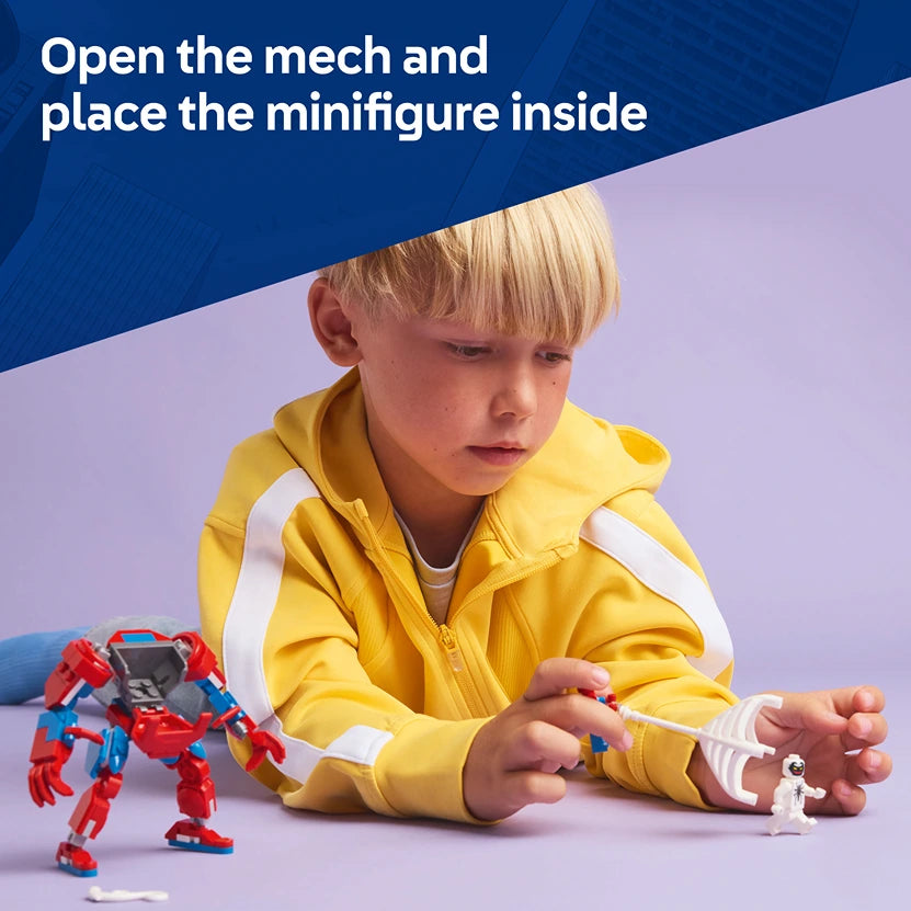 Young child in yellow jacket with white stripes playing with red and blue Lego Spider-Man mech suit, with white Lego minifigure visible on purple background, demonstrating opening mech cockpit to place minifigure inside