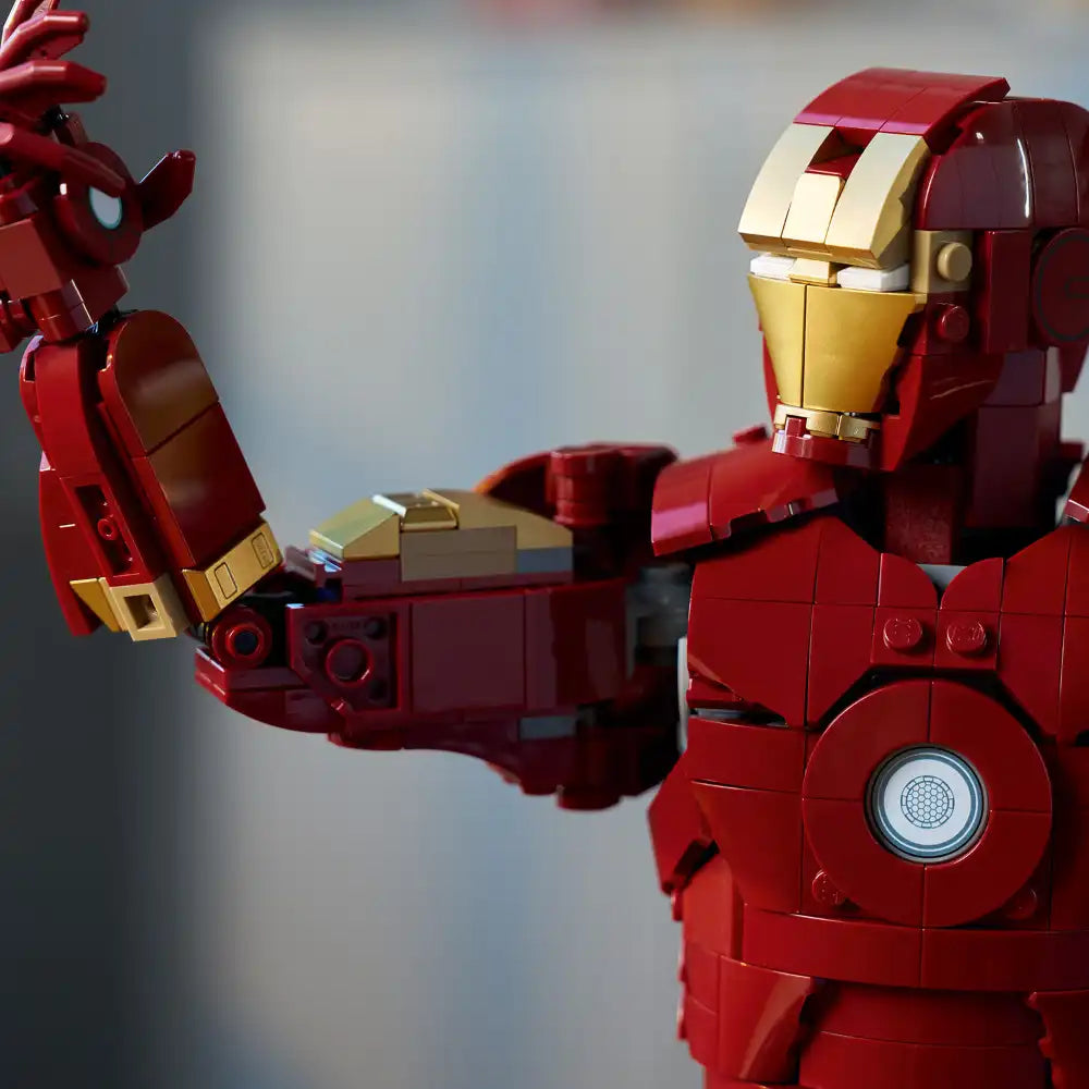 LEGO Iron Man Mark 3 buildable figure in red and gold with detailed armor plating, articulated arms raised in action pose, featuring the iconic arc reactor on chest and helmet with gold faceplate