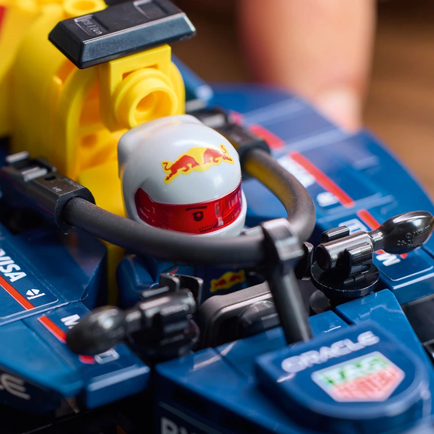 LEGO Oracle Red Bull Racing RB20 F1 race car set featuring a white and red minifigure helmet with Red Bull logo on blue baseplate, yellow pit crane accessory, and detailed black and gray vehicle components