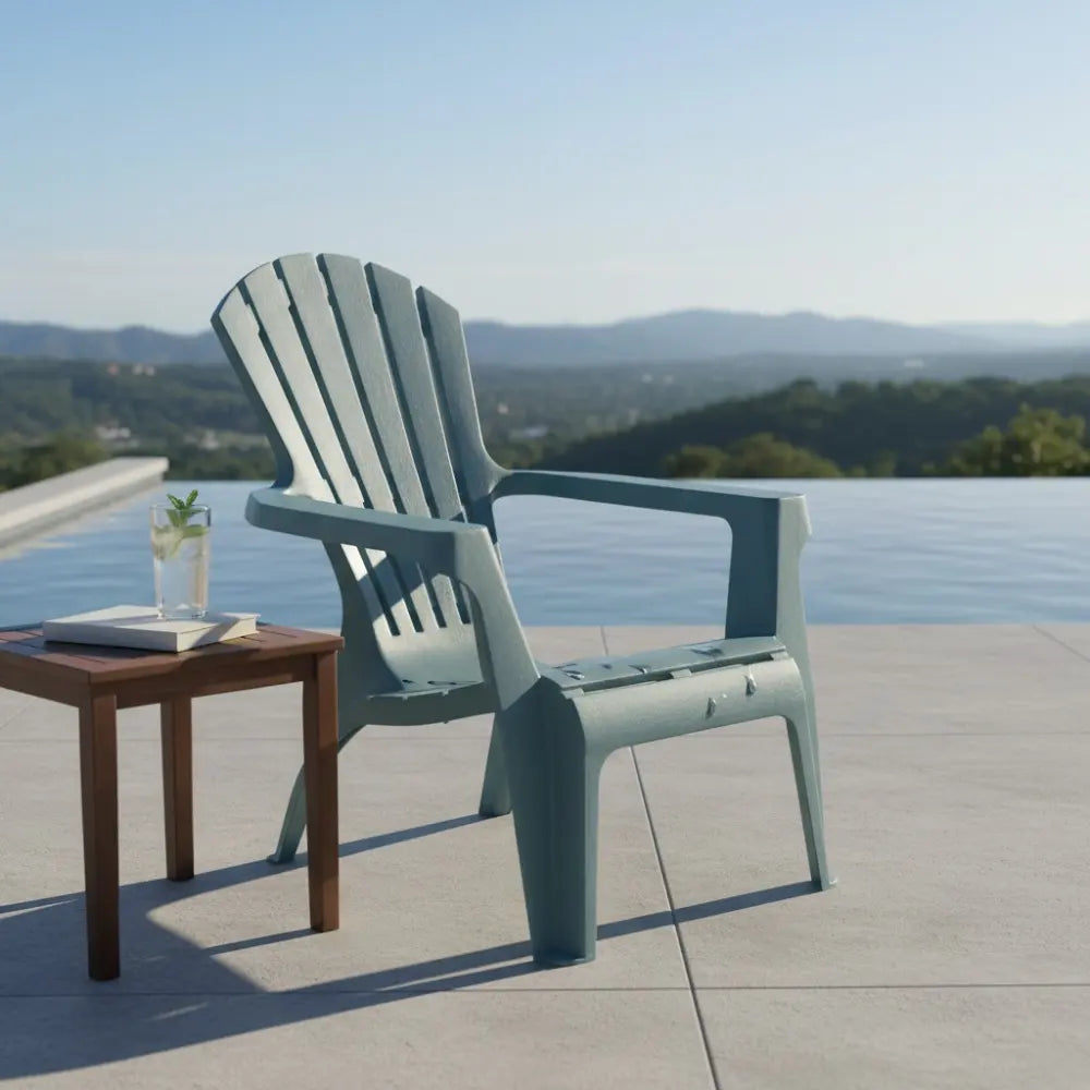 Grey blue modern Adirondack garden chair on a poolside terrace overlooking mountains and forested landscape, with wooden side table holding a glass and book