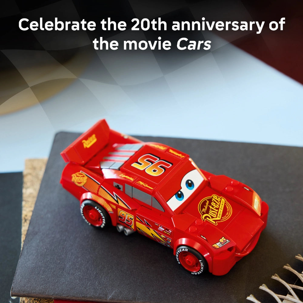 Red LEGO Lightning McQueen car model number 77255 displayed on black surface celebrating 20th anniversary of Pixar Cars movie, featuring number 95 and Rust-eze branding with blue eyes and yellow racing stripes