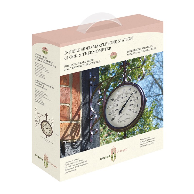 Double-sided Marylebone Station wall clock and thermometer in cream and black with ornate metal bracket, displayed on product packaging showing installation on brick wall with ivy