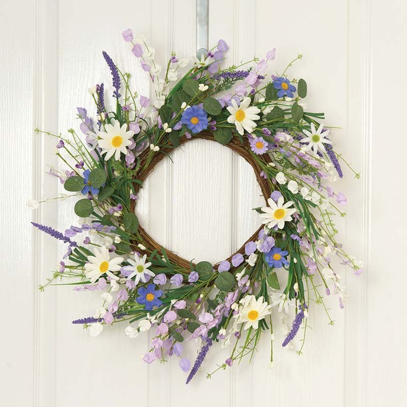 Round grapevine wreath decorated with white daisies, purple and blue flowers, lavender sprigs, and green foliage on white wooden background, 45cm meadow-style garden wreath