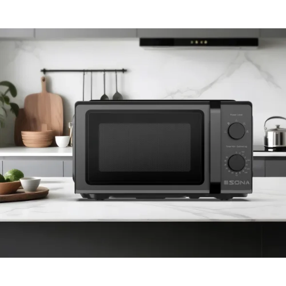 Black Sona 20 litre 700w manual microwave with dual control knobs displayed on a white kitchen countertop, surrounded by wooden kitchen accessories and decorative items in a modern kitchen setting