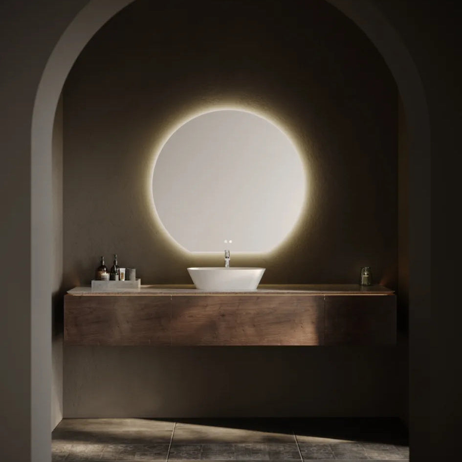 Modern bathroom vanity with round backlit LED mirror in arched alcove, white ceramic vessel sink on dark wood floating countertop, minimalist design with warm ambient lighting