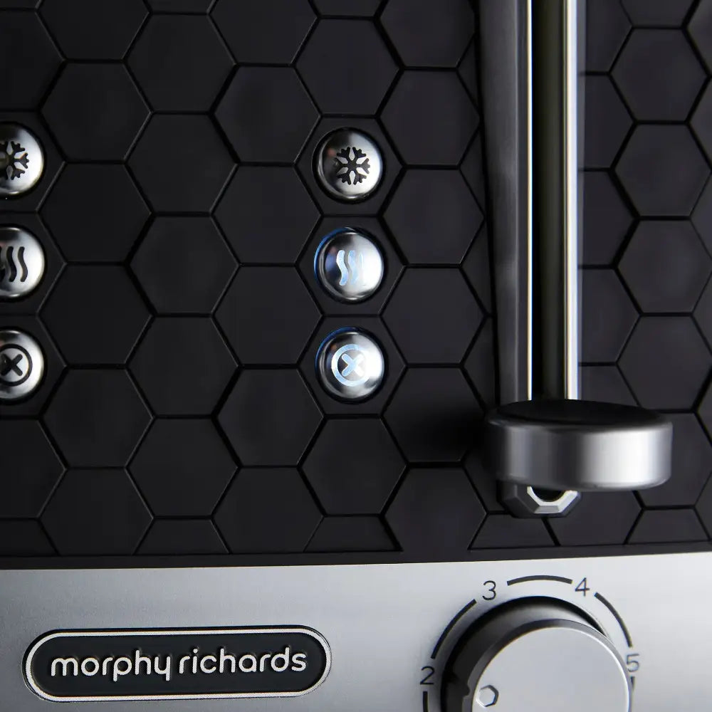 Morphy Richards Cassini 4 slice toaster in black with hexagonal pattern design, featuring illuminated control buttons for temperature and function settings, stainless steel accents, and chrome lever handle against white base panel
