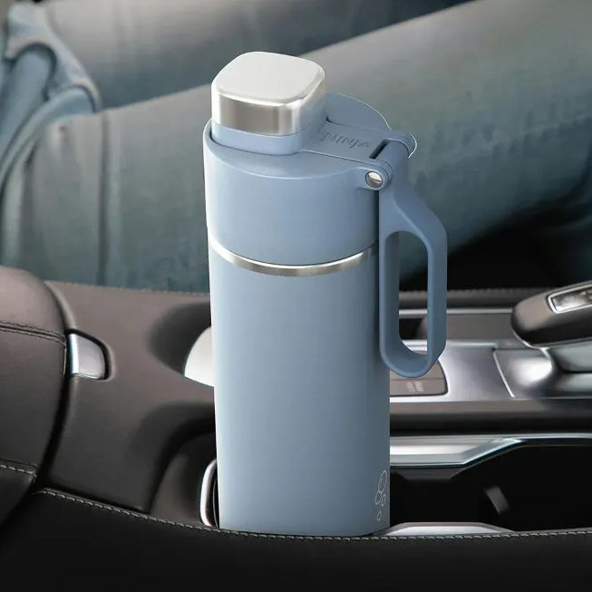 Ninja Thirsti 530ml insulated travel bottle in tropical blue with stainless steel cap and handle, positioned in a car cup holder