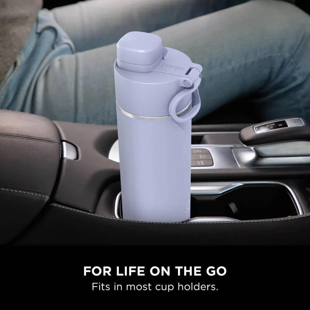 Lavender Ninja Thirsti 530ml insulated travel bottle with carry handle positioned in a car cup holder, demonstrating portable hydration for on-the-go use