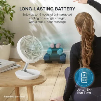 Dimplex white cordless rechargeable 6-inch desk fan displayed on wooden surface next to potted plant, showing long-lasting battery feature with up to 15 hours runtime and 4-hour recharge time
