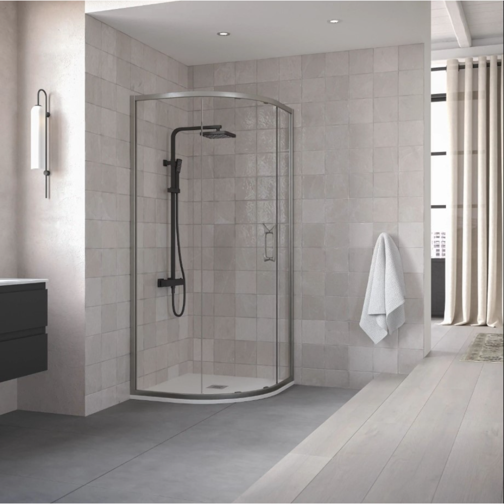Modern bathroom with Flair ETO Quadrant shower enclosure featuring matte black framing and curved glass doors, white subway tile walls, black vanity unit, chrome towel rail, beige curtains and light wood-effect flooring