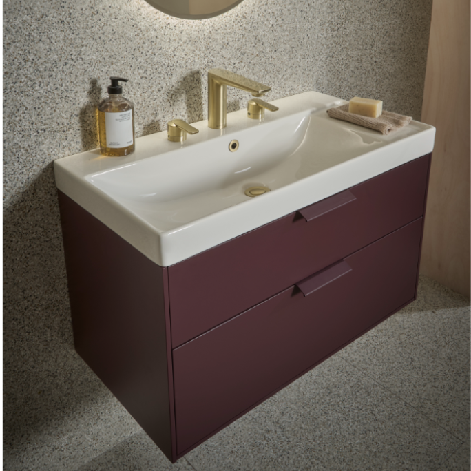 Modern burgundy vanity unit with white ceramic double sink, brass tap fittings, speckled grey splashback, and integrated storage drawers