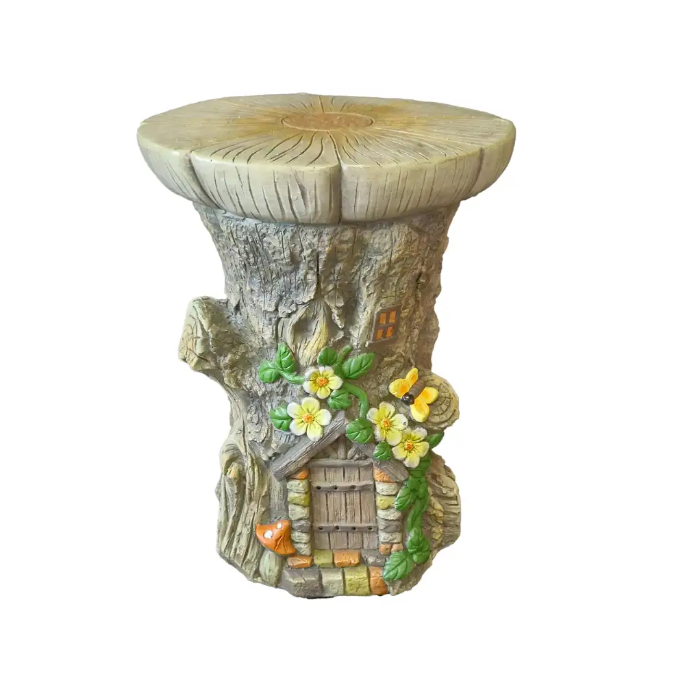 Decorative garden stool with carved tree trunk design featuring fairy house ornament with yellow flowers, green ivy, wooden door and window details in natural stone finish