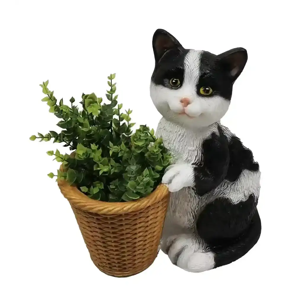 Black and white cat garden planter holding woven wicker basket with green succulent plants, decorative resin figurine with yellow eyes and pink nose on white background