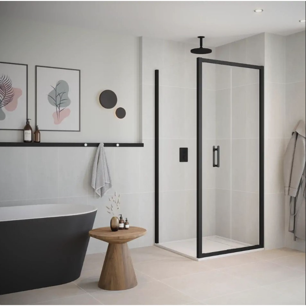 Modern bathroom featuring a black framed bifold shower door with clear glass panels, black freestanding bathtub, wooden side table, white subway tiles, black trim rail, botanical wall art, and ceiling mounted rainfall showerhead