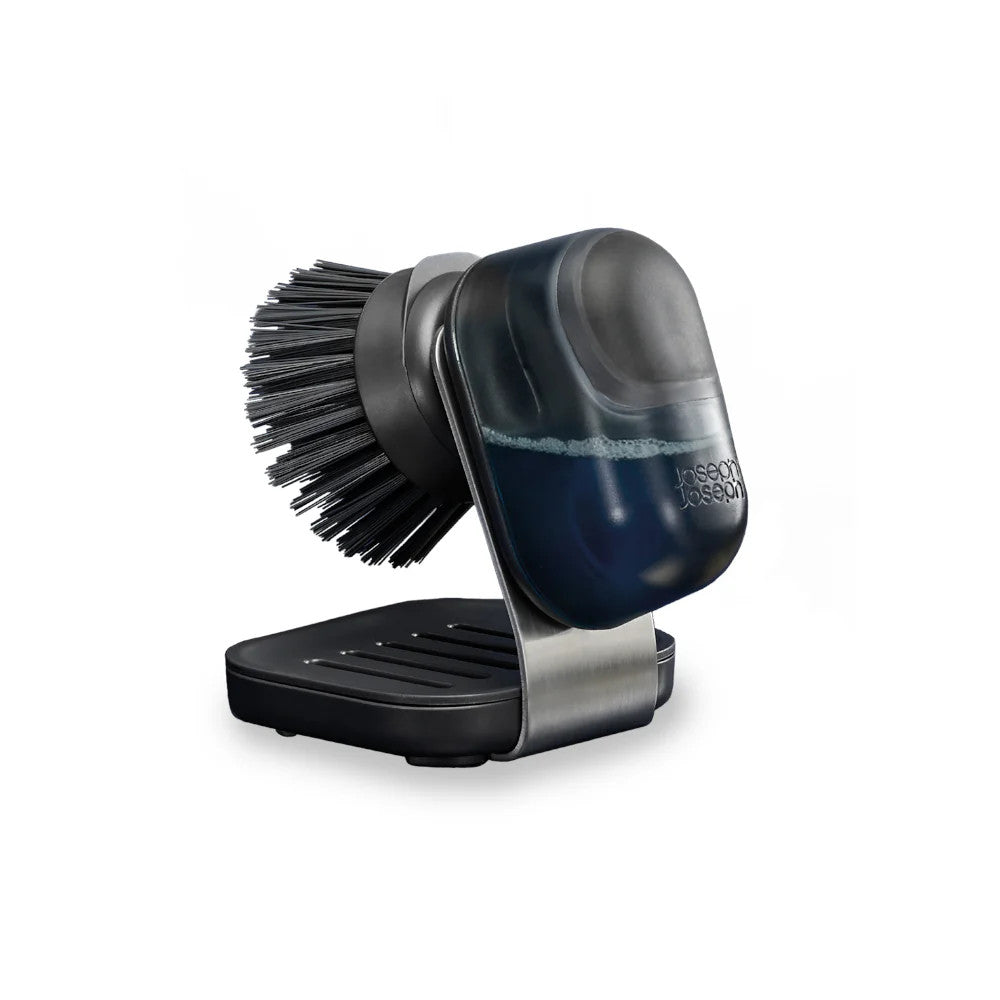 Joseph Joseph SinkTech Soap Dispenser Palm Brush with stainless steel stand, featuring dark navy blue and black design with soft bristles, displayed on white background