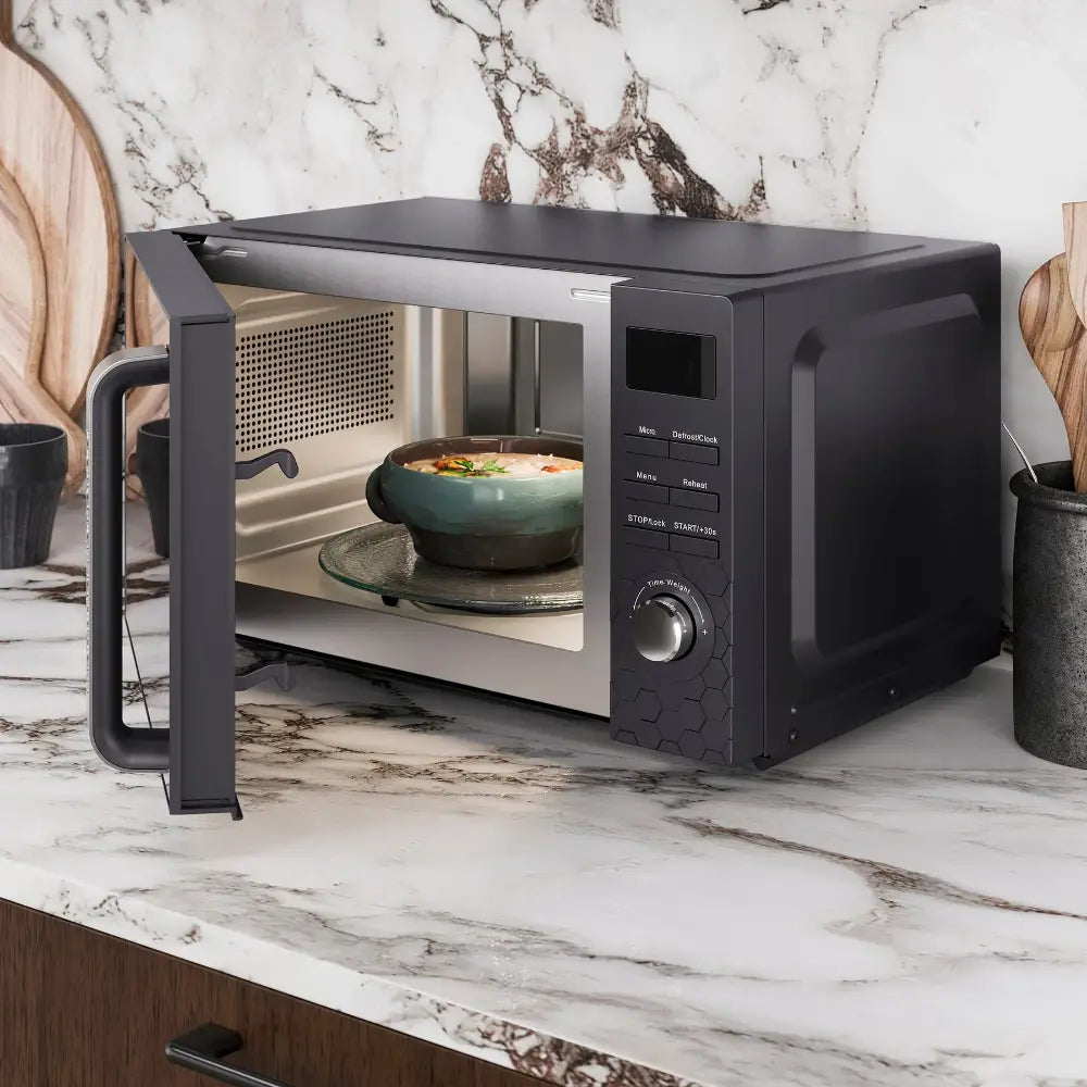 Morphy Richards Cassini Digital Microwave in black with 20 litre capacity, displayed on a marble countertop with open door showing teal bowl of food inside, featuring control panel with digital display and time dial on right side